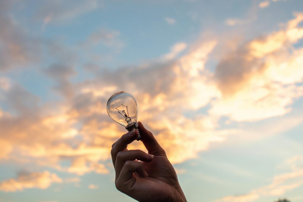 Mano sosteniendo una bombilla con el cielo al atardecer de fondo, simbolizando una idea innovadora en el sector náutico.